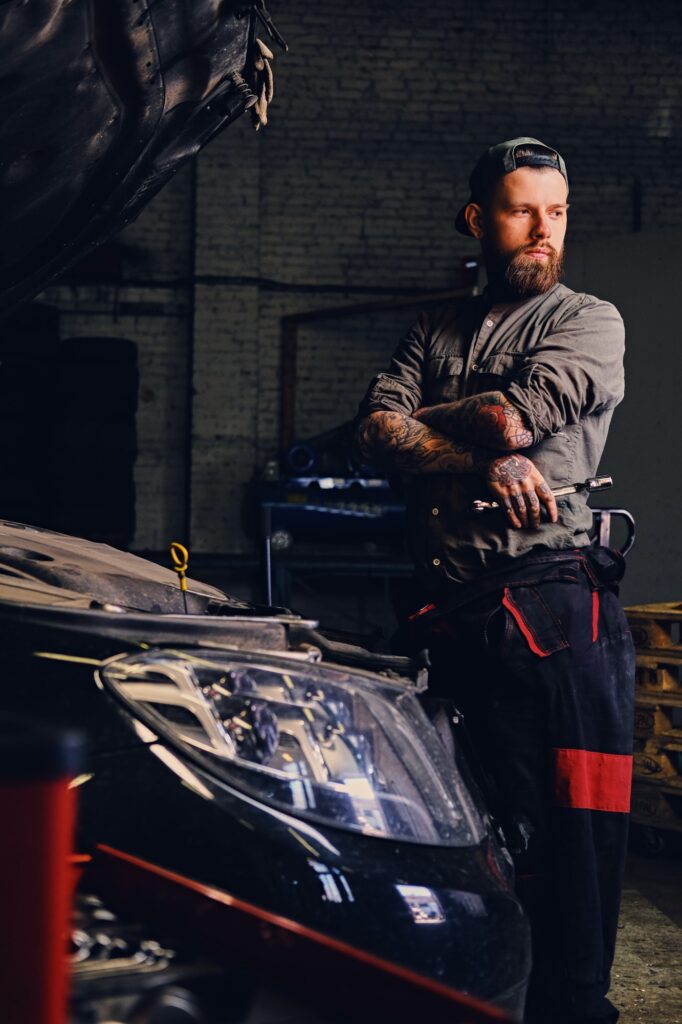 Bearded mechanics with crossed arms posing near a car.